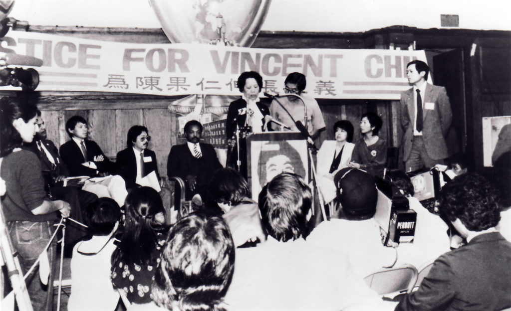 Image description: Reverend Jesse Jackson and Lily Chin, the mother of Vincent Chin, at a community event, demanding justice for Vincent Chin after his violent death. Former CAA Executive Director, Henry Der, is also pictured beneath a banner that reads, "Justice for Vincent Chin!" first in English and then in Chinese. The protest took place at Cameron House in San Francisco Chinatown. 