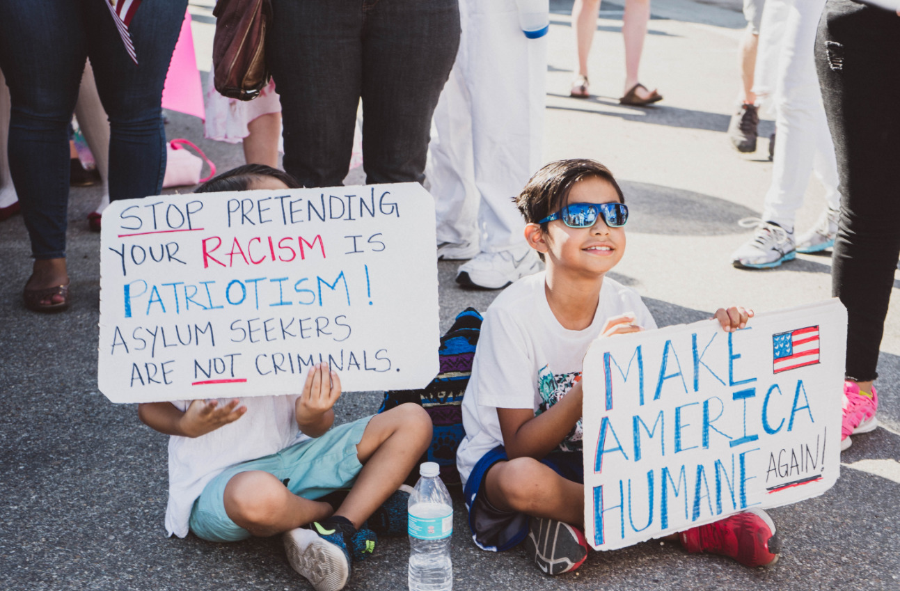 Two children holding signs demanding justice for asylum seekers