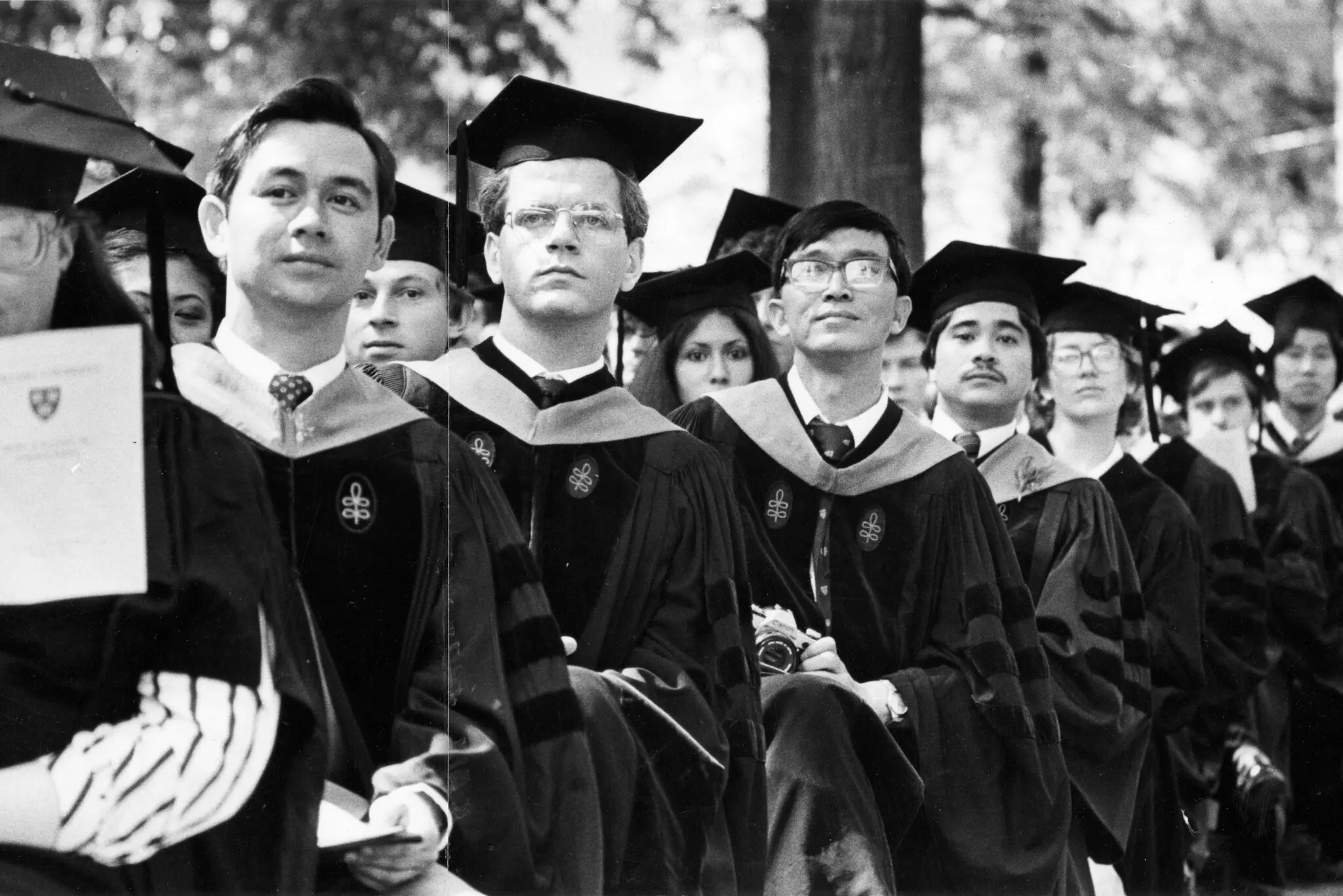 A black and white photo of mostly white men matriculated at Harvard with one Asian American student.