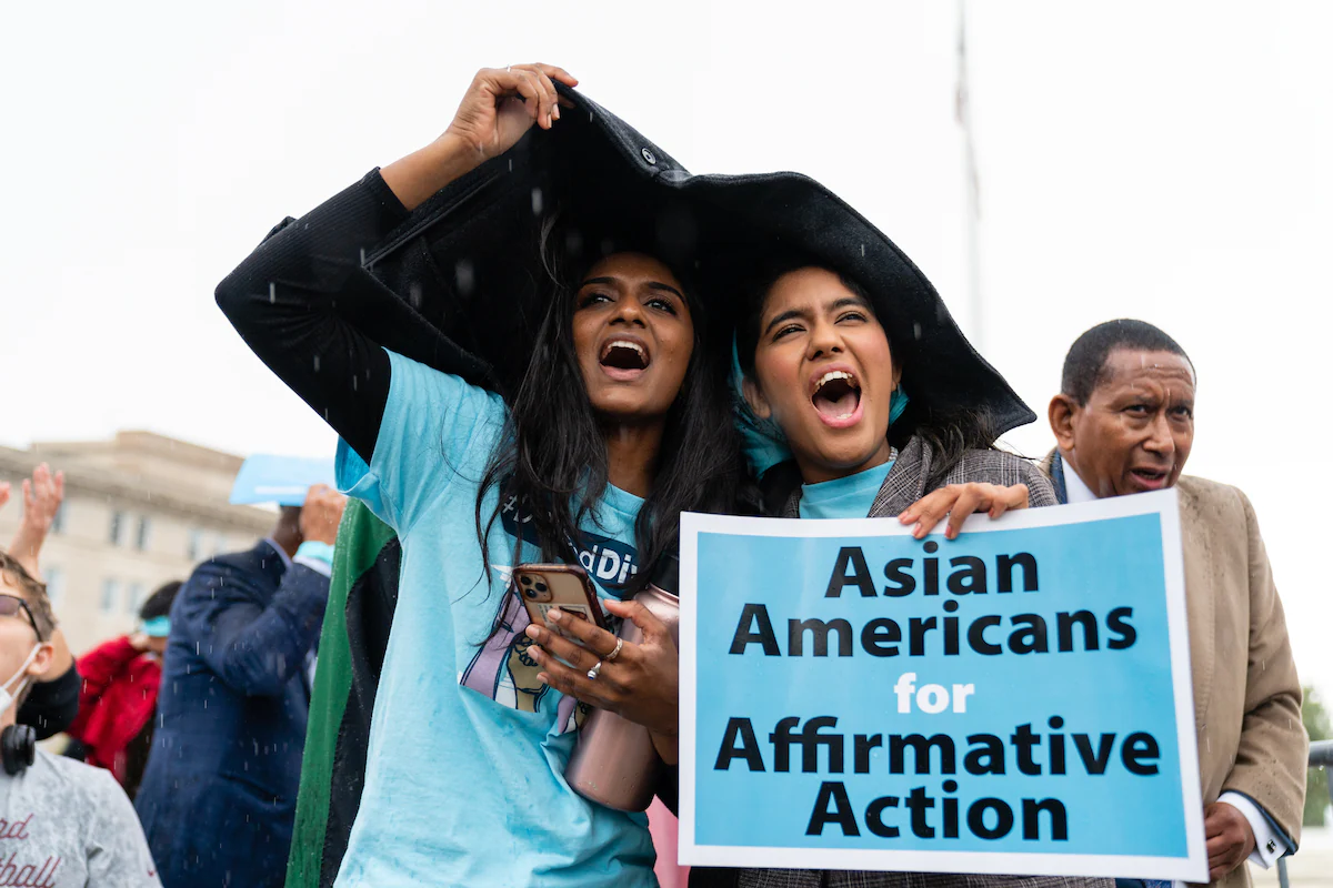 Students rallying in front of the Supreme court wearing signature blue carrying signs that state Asian American for Affirmative Action