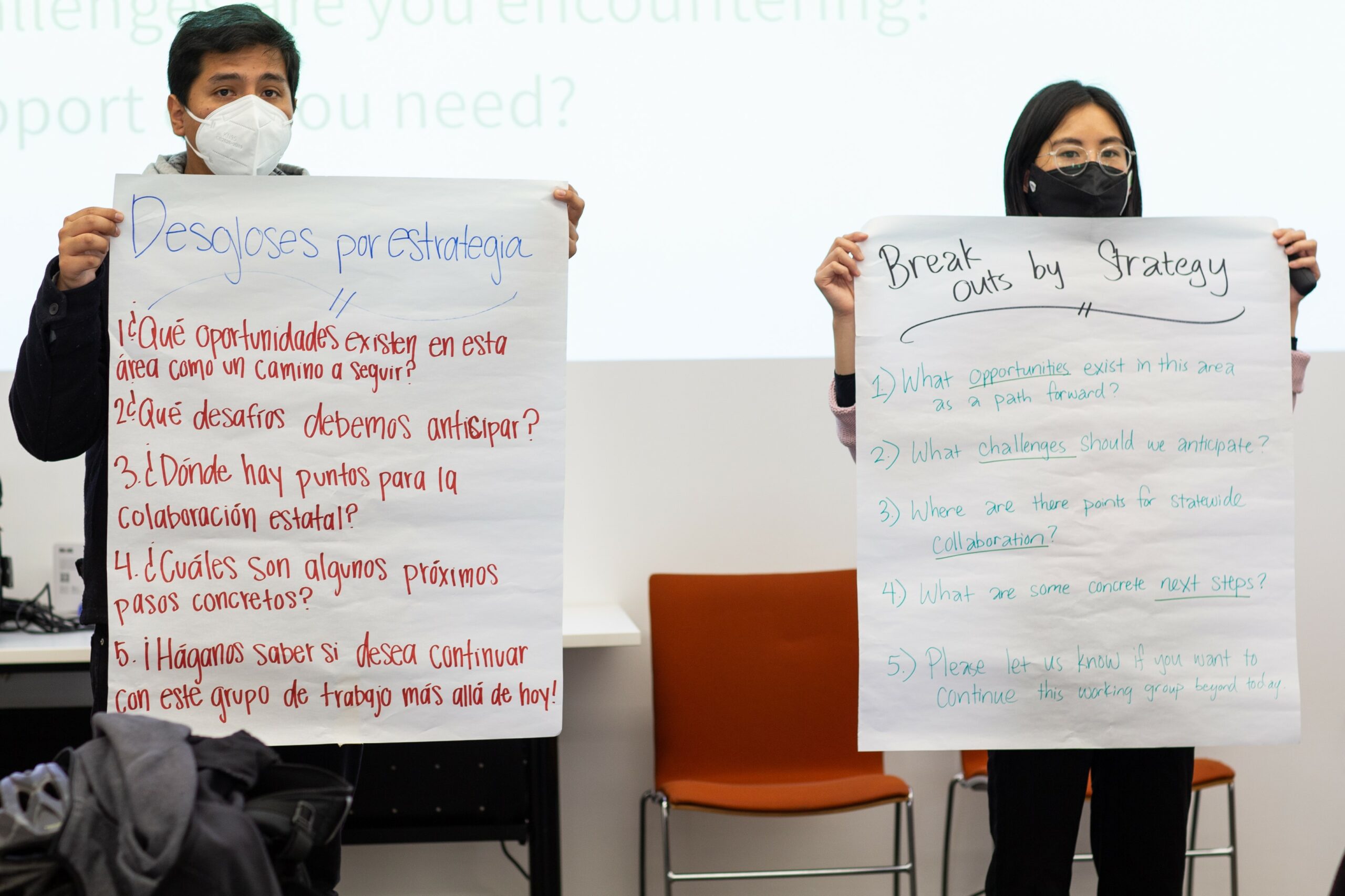 Two people holding up a large stickie with writing