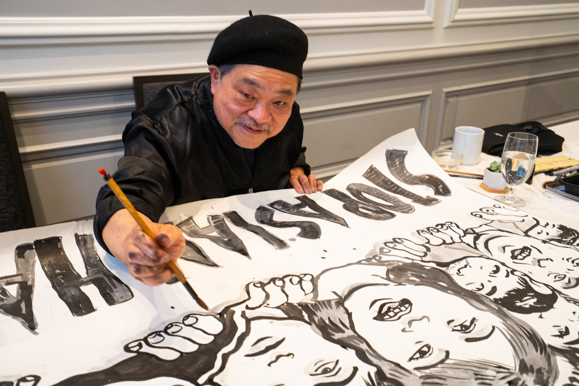 Artist Leland Wong painting a Stop Asian Hate piece.